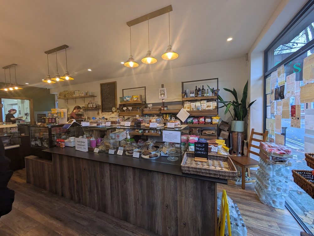 Looking down the long timber counter and cake display towards the window under pendant lights