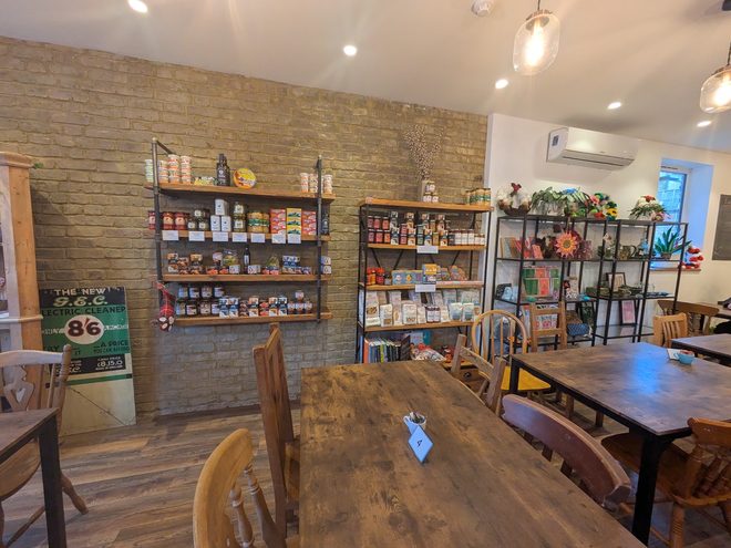 Interior corner with wooden tables and mismatched chairs beside stocked shelving