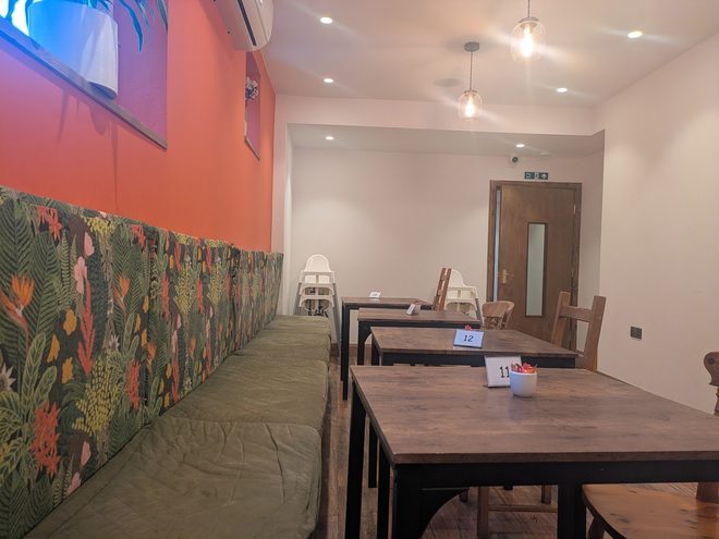 The terracotta-and-mural dining room seen from the rear of the café